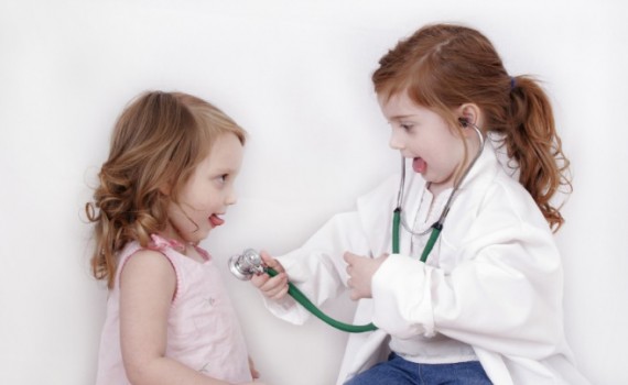 Little girl with stethoscope listening to her sister's heart