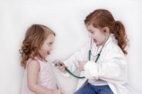 Little girl with stethoscope listening to her sister's heart